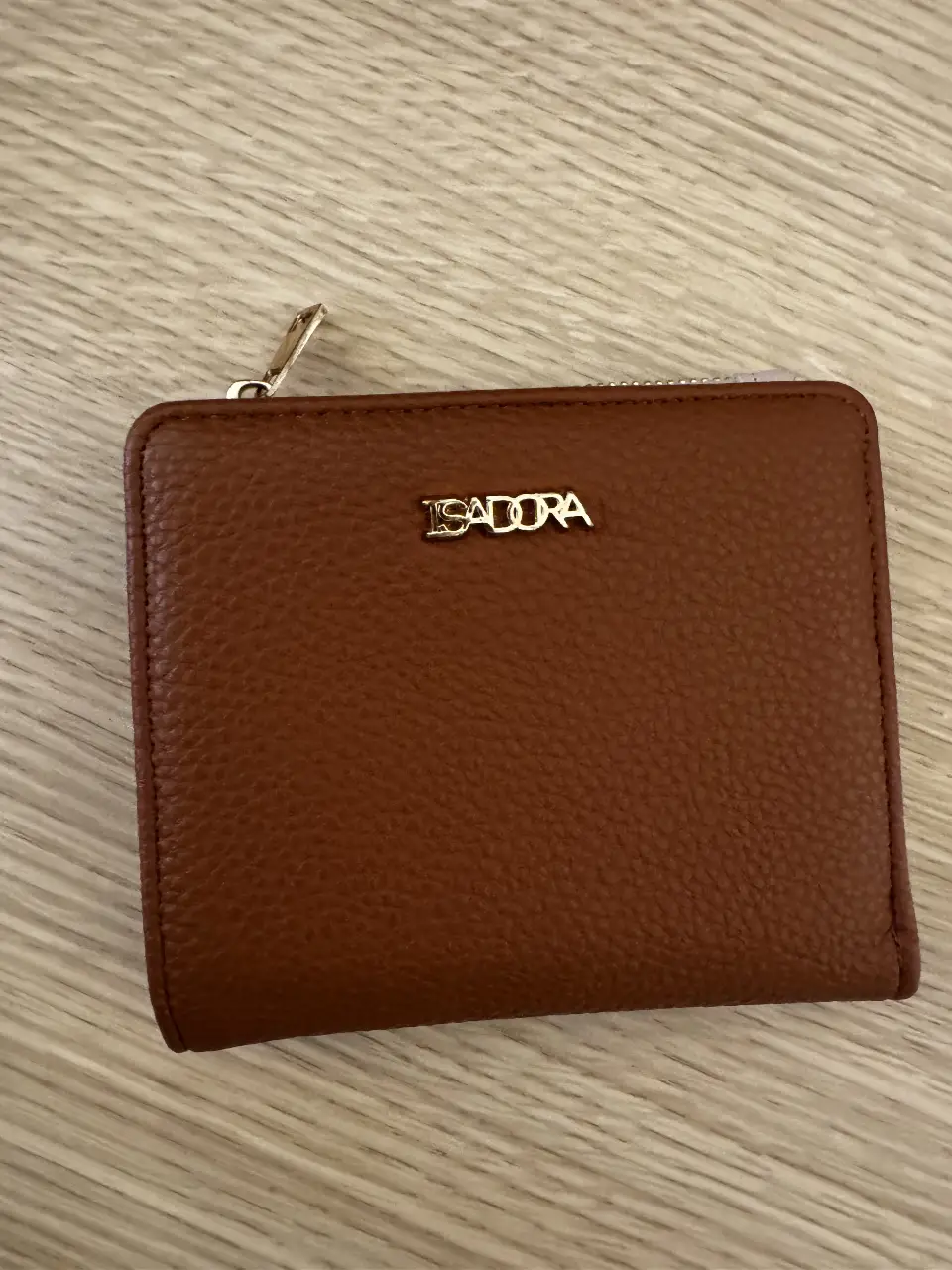 Billetera ISADORA de cuero marrón, con cierre y varios compartimentos internos. Ideal para organizar tus pertenencias con estilo y elegancia.