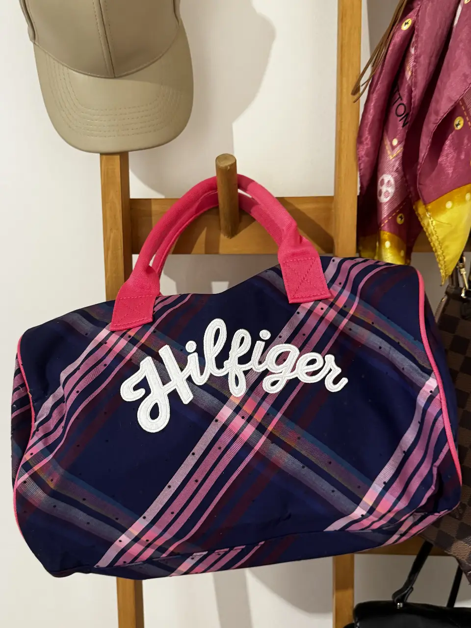 Bolso deportivo Tommy Hilfiger a cuadros azul y rosa, con manijas y detalles en rosa. Ideal para llevar al gimnasio o para viajes cortos.