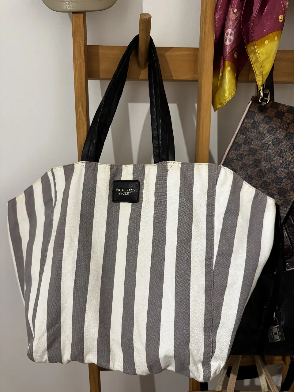 Bolso tote de Victoria's Secret a rayas grises y blancas, con manijas negras y detalle de la marca. Ideal para llevar todo lo que necesitas con estilo.