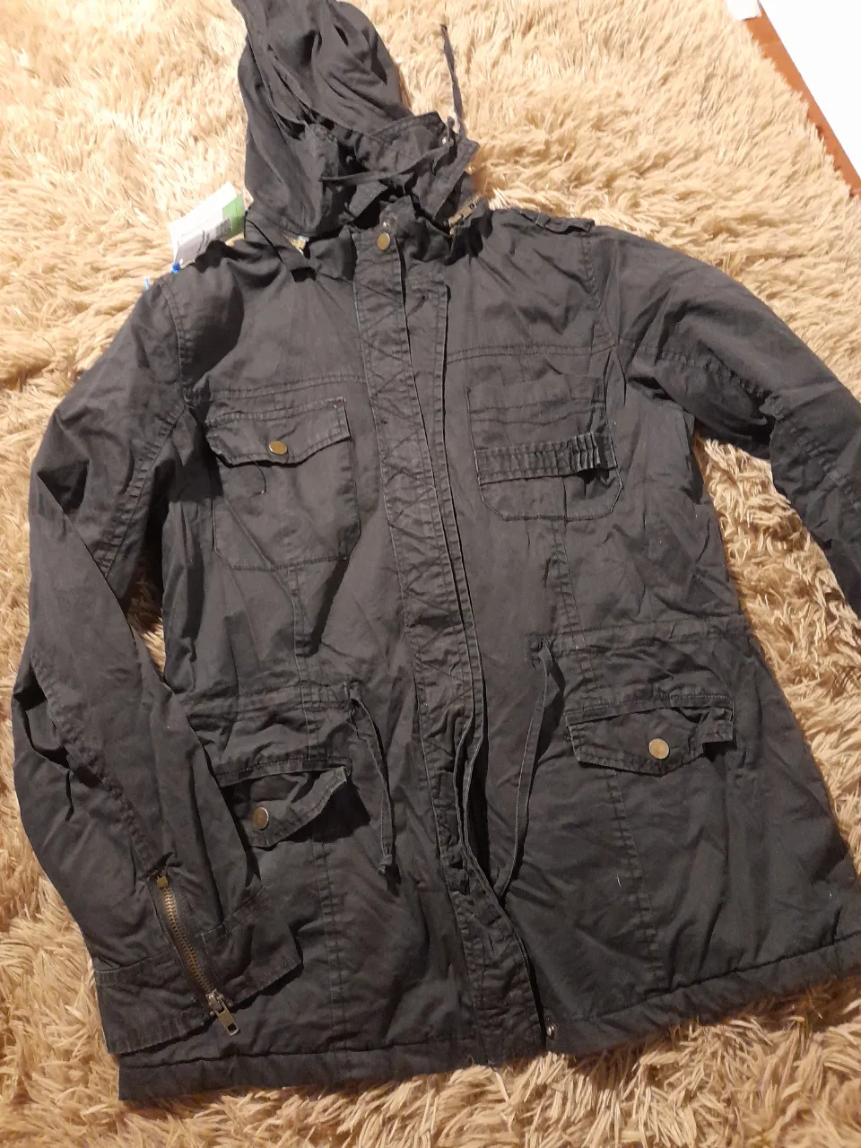 Parka negra .Sin peluche .Forrada 
Talle L 
Medidas: largo total 71cm. Axila/axila 46cm. Largo de manga 58cm. 
2 bolsillos .Con broches y cierre.
Capucha desmontable
Con detalle  en broche del bolsillo. .