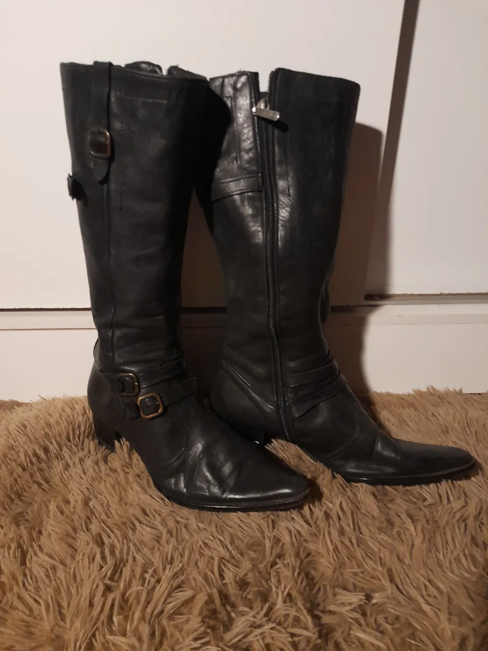 Botas de cuero negras, caña alta, con hebillas y cierre lateral. Taco bajo.