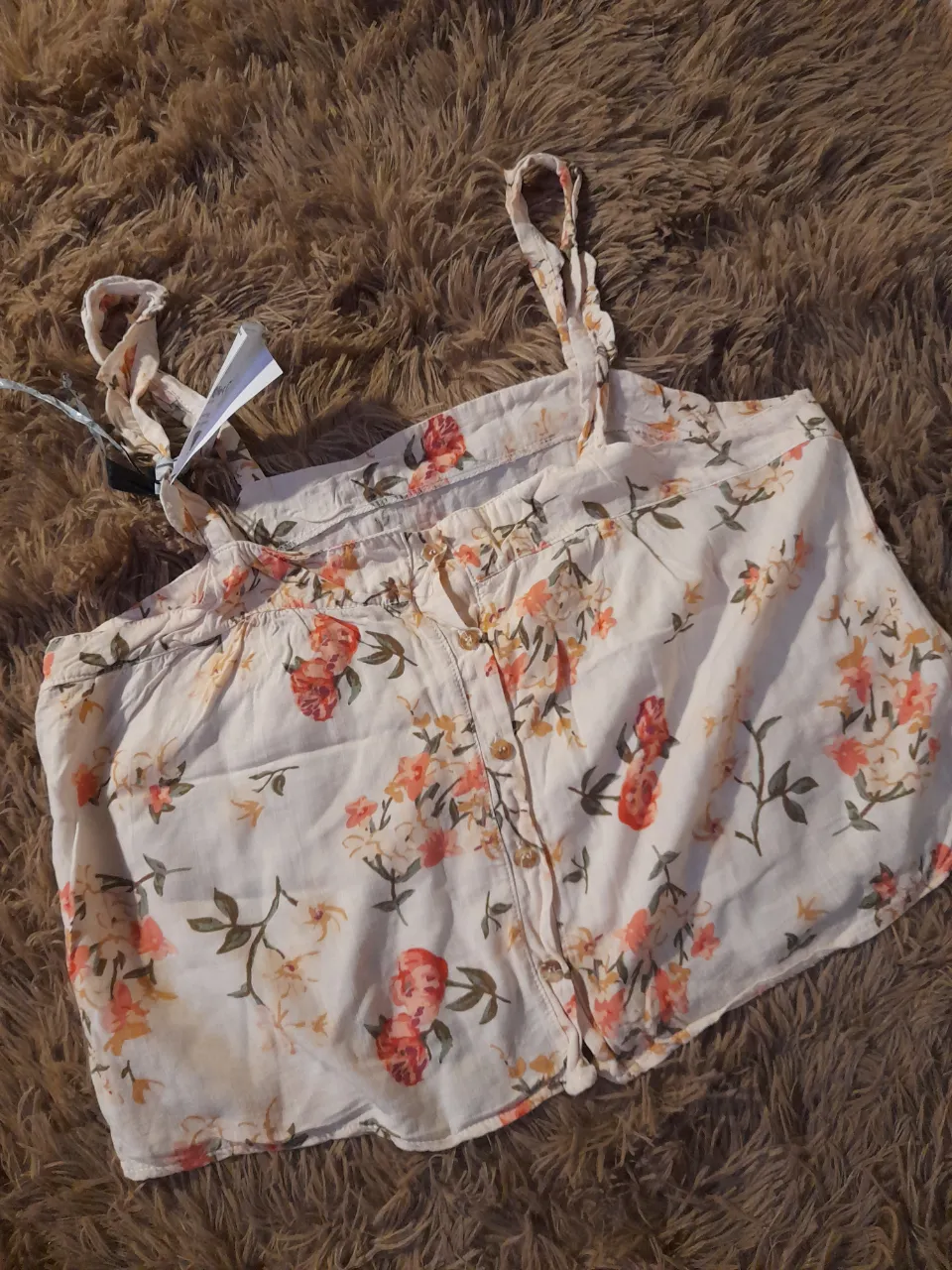 Top de breteles finos con estampa floral. Posee botones en la parte delantera y lazos en los breteles para ajustar.