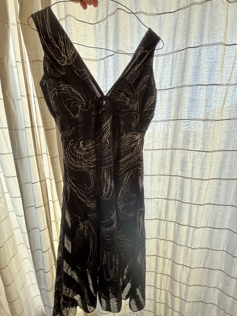 Vestido negro con estampado abstracto en blanco y plateado. Diseño con escote en V y breteles anchos corte princesa. Ideal para una salida o fiesta.