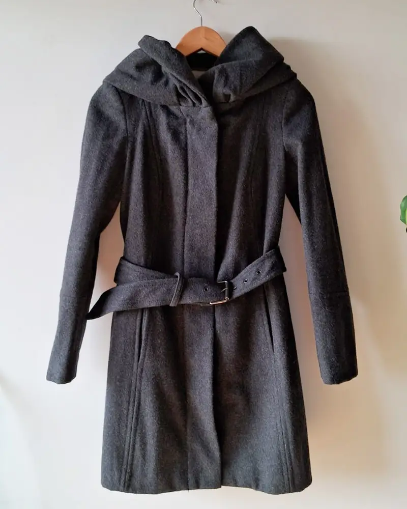 Tapado marca Zara de paño gris oscuro con capucha, cinturón y cierre frontal. Talle XS. Medidas aprox: hombros 36cm, entre sisas 42cm, cintura 40cm, largo 86cm. Composición: 56% lana, 44% poliester.
