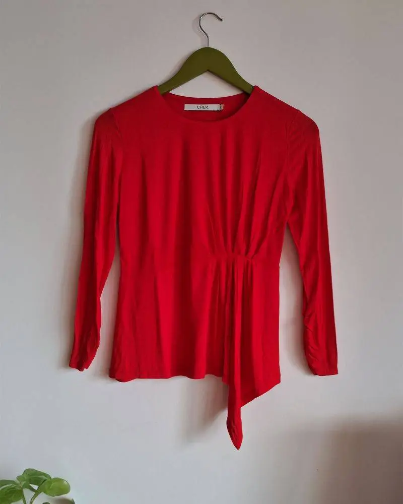 Remera roja Maria Cher. Manga larga, escote redondo. Detalle de frunce y pico asimétrico, y frunces en puños. Nueva, sin etiqueta. Talle 2. Medidas aproximadas: hombros 36cm, entre sisas 43cm, largo 57cm. Composición: 93% viscosa, 7% elastano.