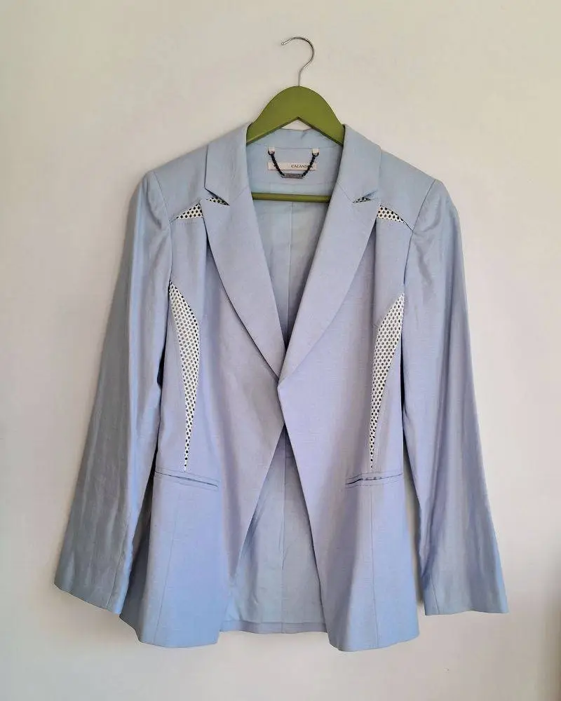 Blazer celeste marca Calandra con detalles calados en blanco. Con hombreras. Las etiquetas no especifican talle, puede ser S o M. Medidas aproximadas: hombros 40cms, entre sisas 42cms, largo 70cms, largo de mangas 59cms. Composición: 53% lino, 44% rayon, 3% spandex