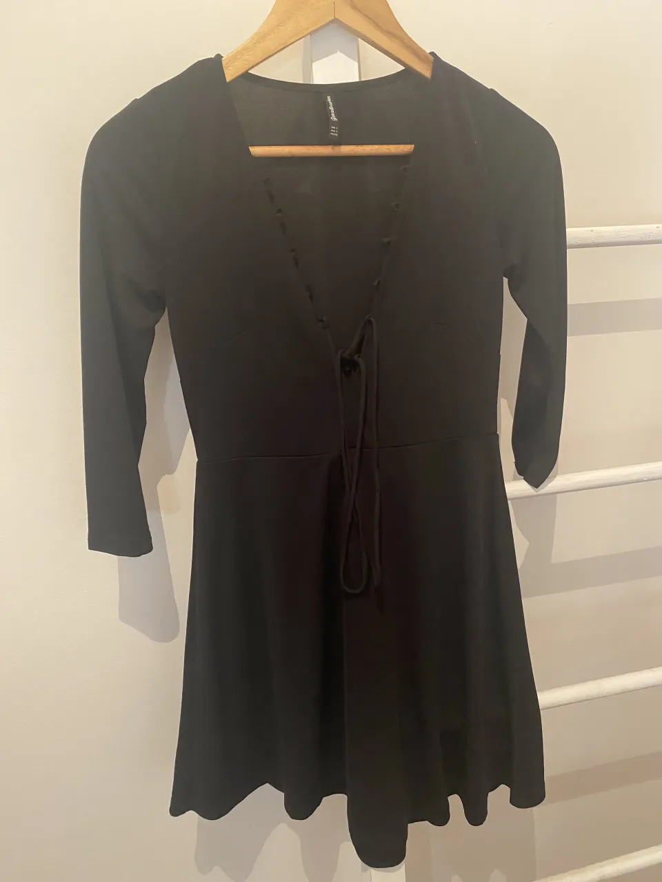 Vestido negro de manga larga con escote en V y detalle de lazo. Ideal para un look casual o para salir.