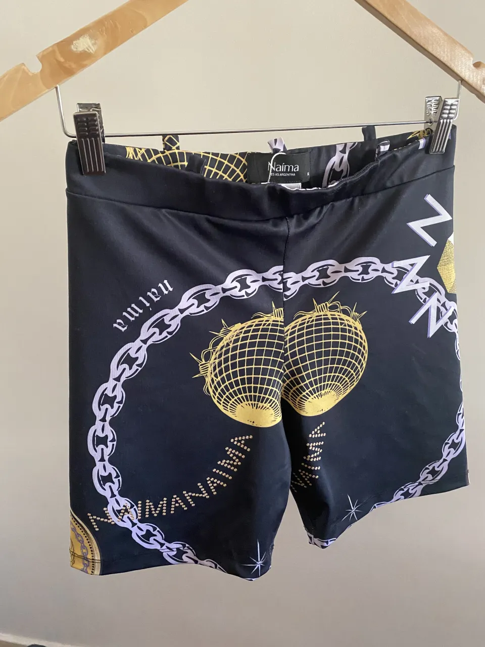 Shorts de lycra negros con estampa exclusiva de cadenas y discos dorados. Ideales para entrenar o para un look urbano.