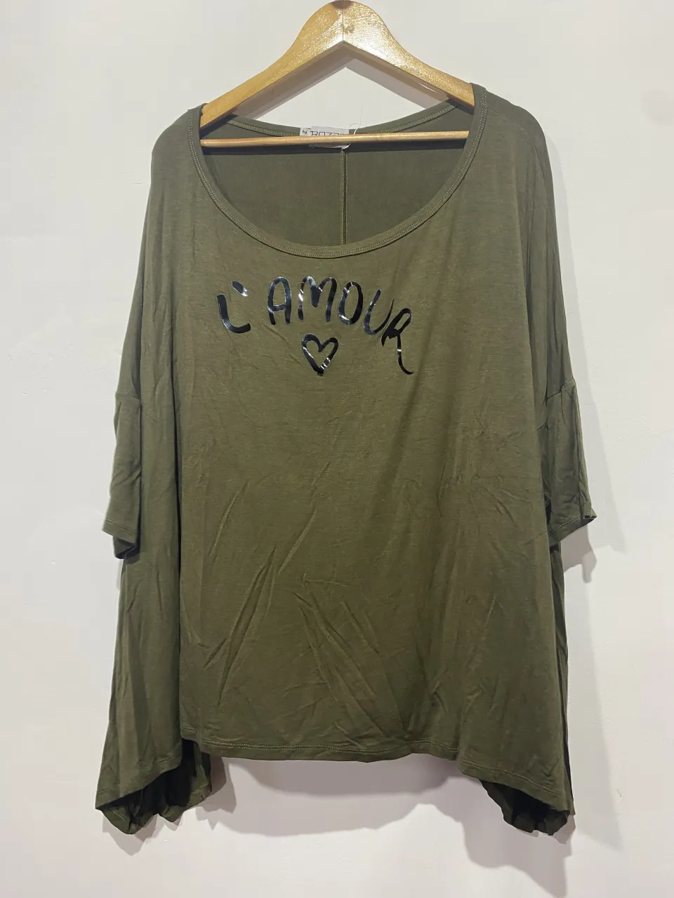 Remera manga corta color verde militar con estampa "L'AMOUR" y corazón. Diseño holgado y moderno, ideal para un look casual y canchero.