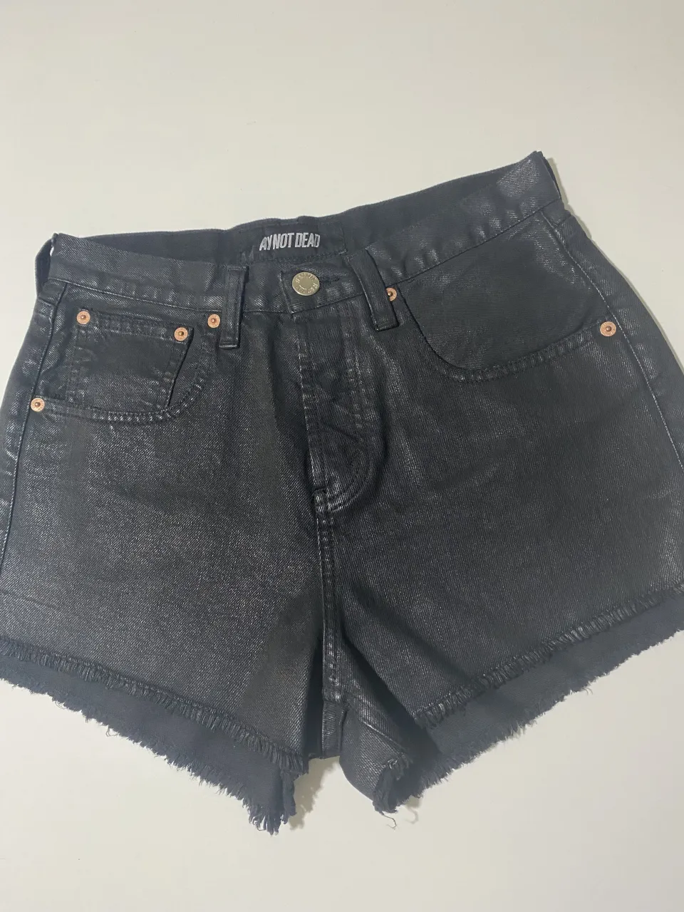 Shorts de jean negros tiro alto con roturas y detalles deshilachados en el ruedo. Un básico moderno para cualquier look.
