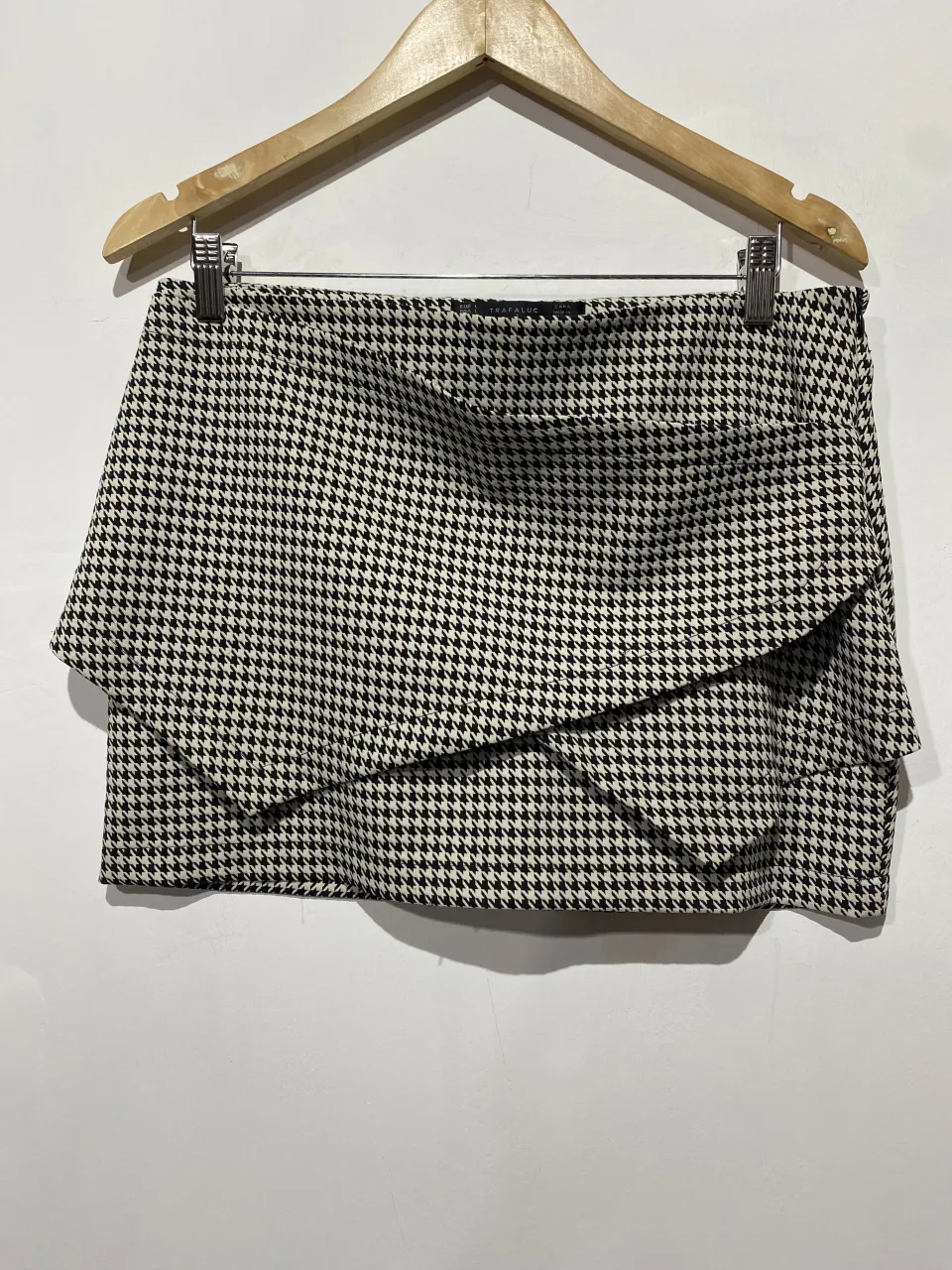 Pollera corta con estampado pata de gallo y diseño de volados superpuestos. Ideal para un look canchero y moderno.