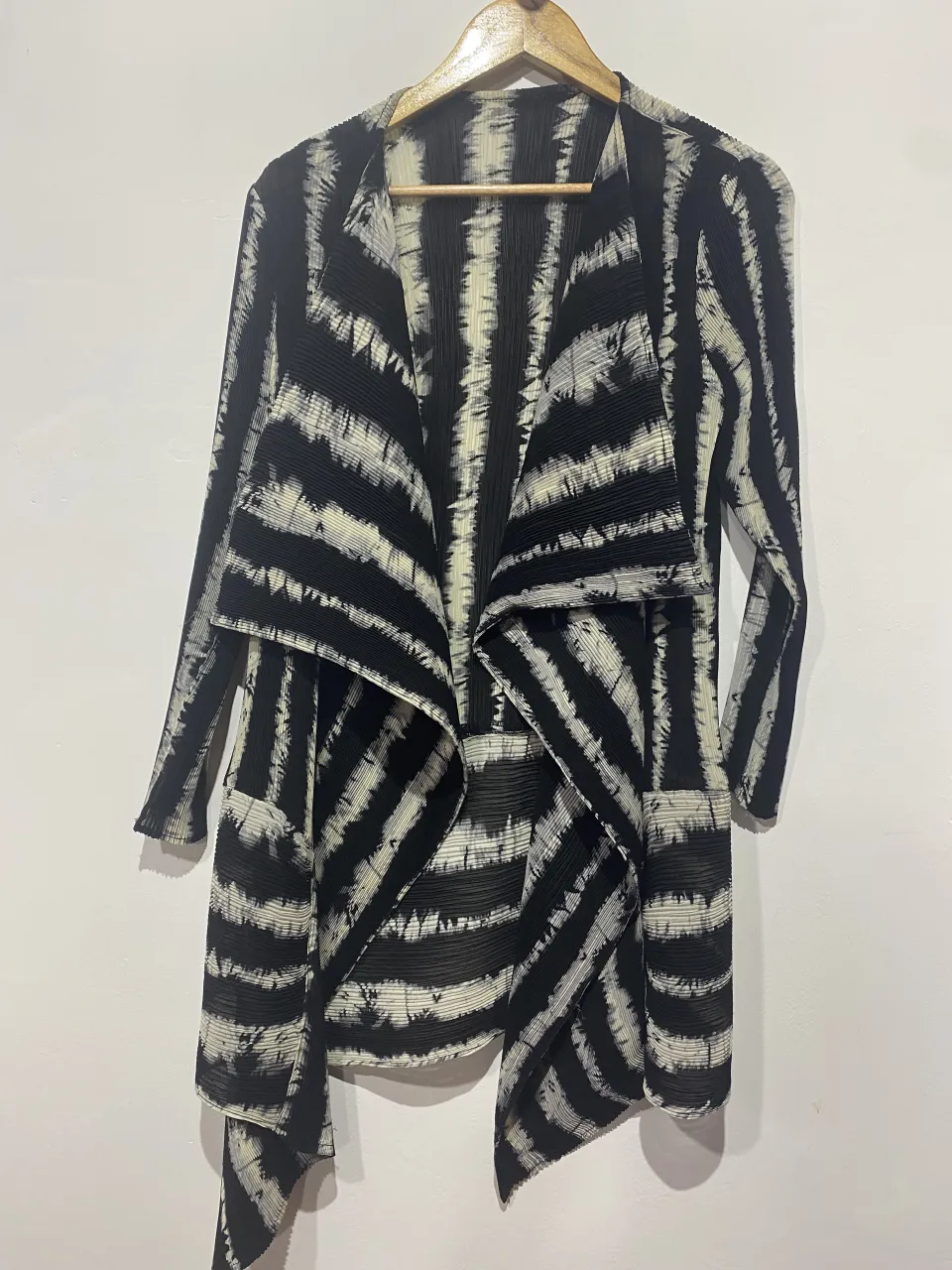 Cardigan largo con estampado de rayas verticales y horizontales en blanco y negro. Posee solapas amplias y un corte asimétrico con caída.