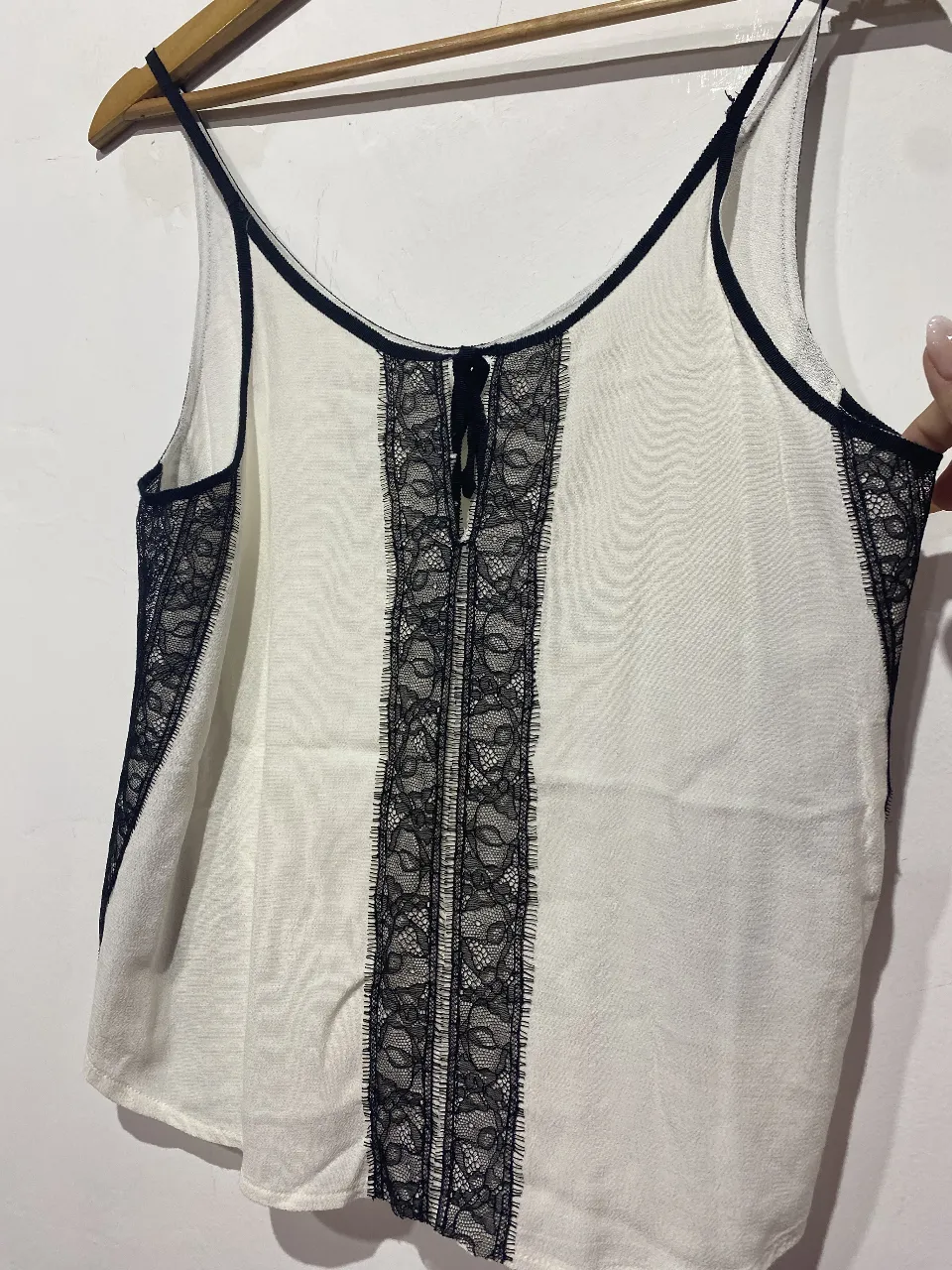 Top blanco con detalles de encaje negro y tiras finas. Ideal para un look delicado y femenino.