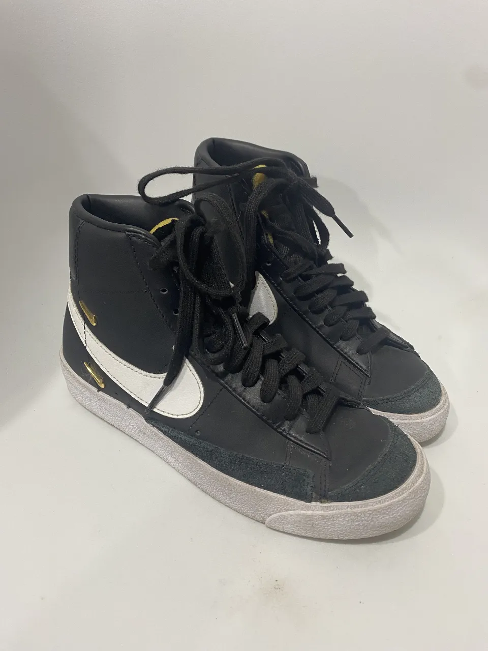 Zapatillas Nike Blazer Mid '77 Vintage, un clásico reinventado. Diseño de caña alta en cuero negro con detalles en blanco y el icónico swoosh. Perfectas para un look urbano y canchero.