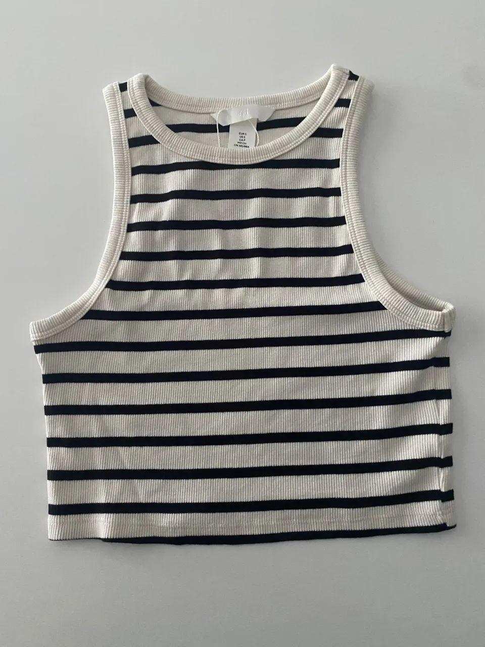 Musculosa a rayas blancas y negras, con cuello redondo y corte al cuerpo. Ideal para un look casual y canchero.