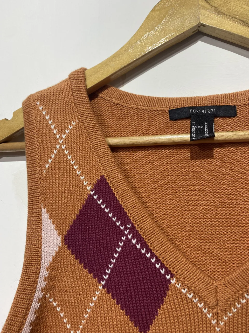 Sweater sin mangas de tejido con rombos en color naranja, bordo y rosa pálido. Escote en V.