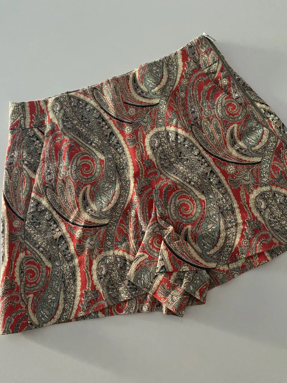 Shorts de estampado paisley en tonos rojos, grises y crudos. Ideales para un look canchero y fresco.