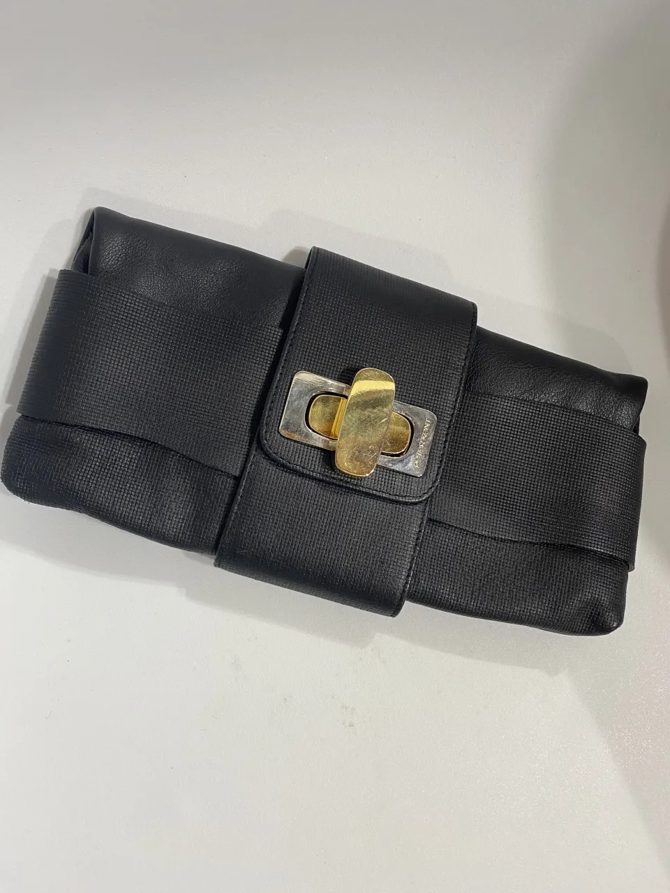 Cartera de mano negra, ideal para complementar tu look de fiesta o salida. Posee un diseño elegante con detalles metálicos dorados y plateados en el cierre.