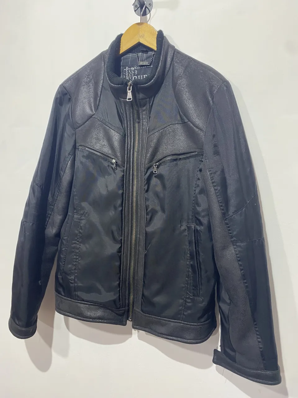 Campera de cuero negra Guess, ideal para un look rocker o casual. Con cierre al frente y bolsillos con cierre. Interior forrado a cuadros.