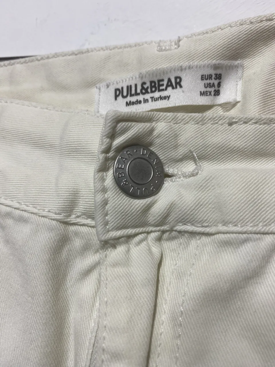 Pantalón cargo color crudo de la marca Pull&Bear. Posee bolsillos laterales con tapa y un pequeño detalle de mancha en la parte delantera.