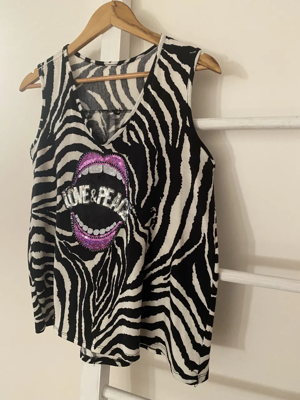 Musculosa súper canchera con estampa de cebra y labios con brillos que dicen "LOVE & PEACE". Ideal para un look audaz y divertido.