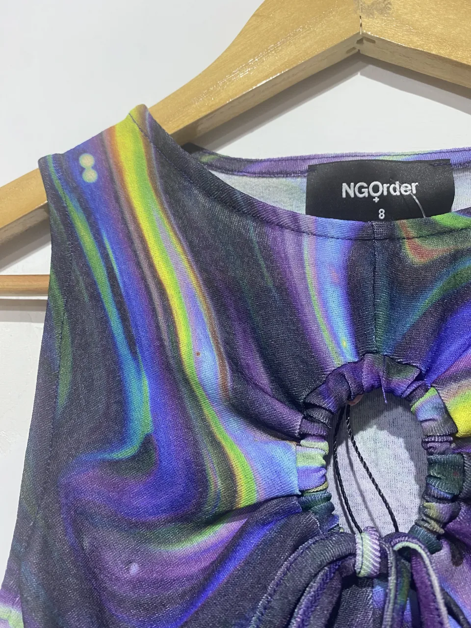 Top súper canchero con estampa psicodélica en tonos vibrantes de violeta, azul, verde y amarillo. Diseño con fruncido y lazo en el frente, ideal para un look audaz y moderno. Perfecto para combinar con jeans o shorts.