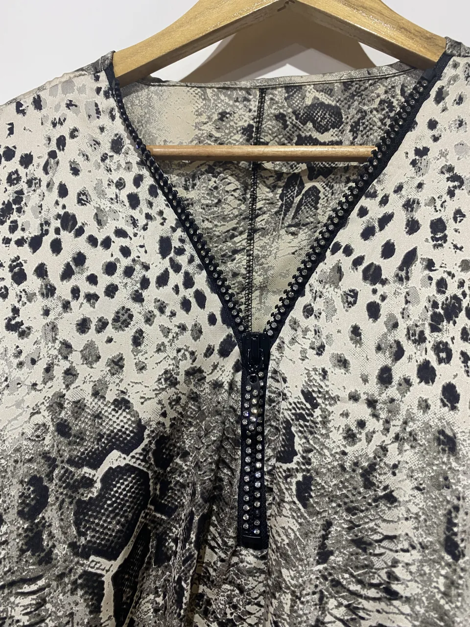 Blusa con estampa animal print y detalles de serpiente. Posee cierre metálico con strass en el frente.