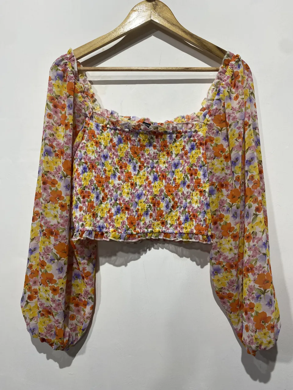 Top floreado súper canchero con mangas largas abullonadas y escote cuadrado. El torso es fruncido, lo que le da un calce perfecto y muy favorecedor. Ideal para un look de día o de noche.