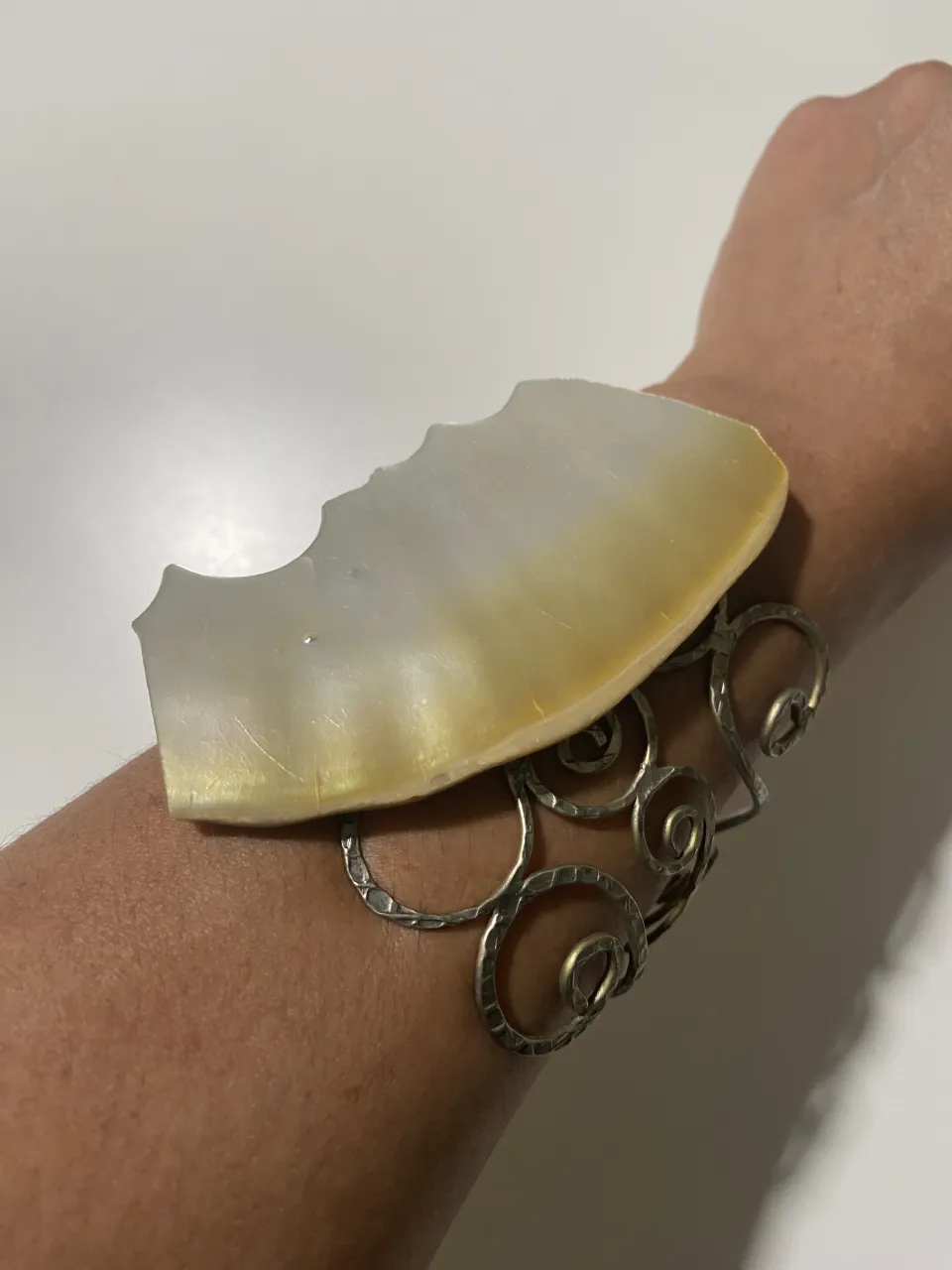 Pulsera de plata con piedra natural iridiscente. Diseño único con espirales y detalles martillados. Ideal para un look bohemio y elegante.