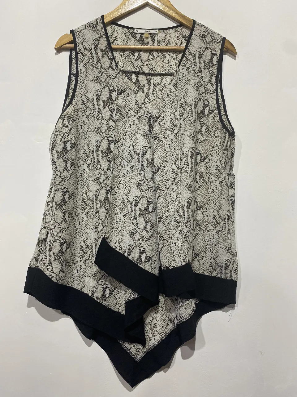 Musculosa estampada con diseño de serpiente y detalles en negro. Posee un corte asimétrico y es ideal para un look canchero y moderno.