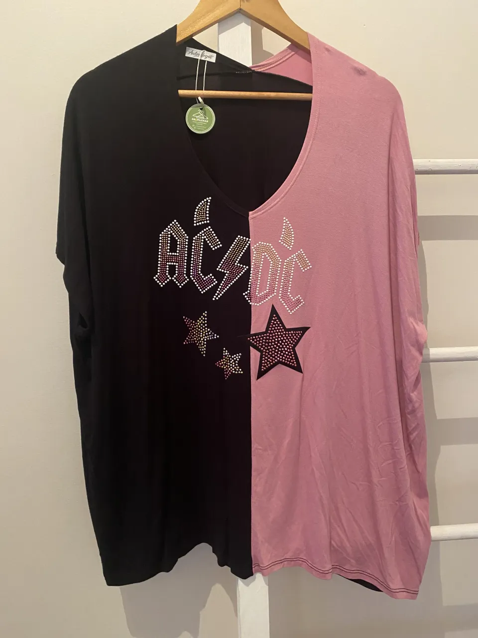Remera súper canchera y original, con un diseño dividido en dos colores: negro y rosa. En el frente, tiene el logo de AC/DC y estrellas estampadas con strass, dándole un toque rockero y brillante. Ideal para un look descontracturado y con onda.
