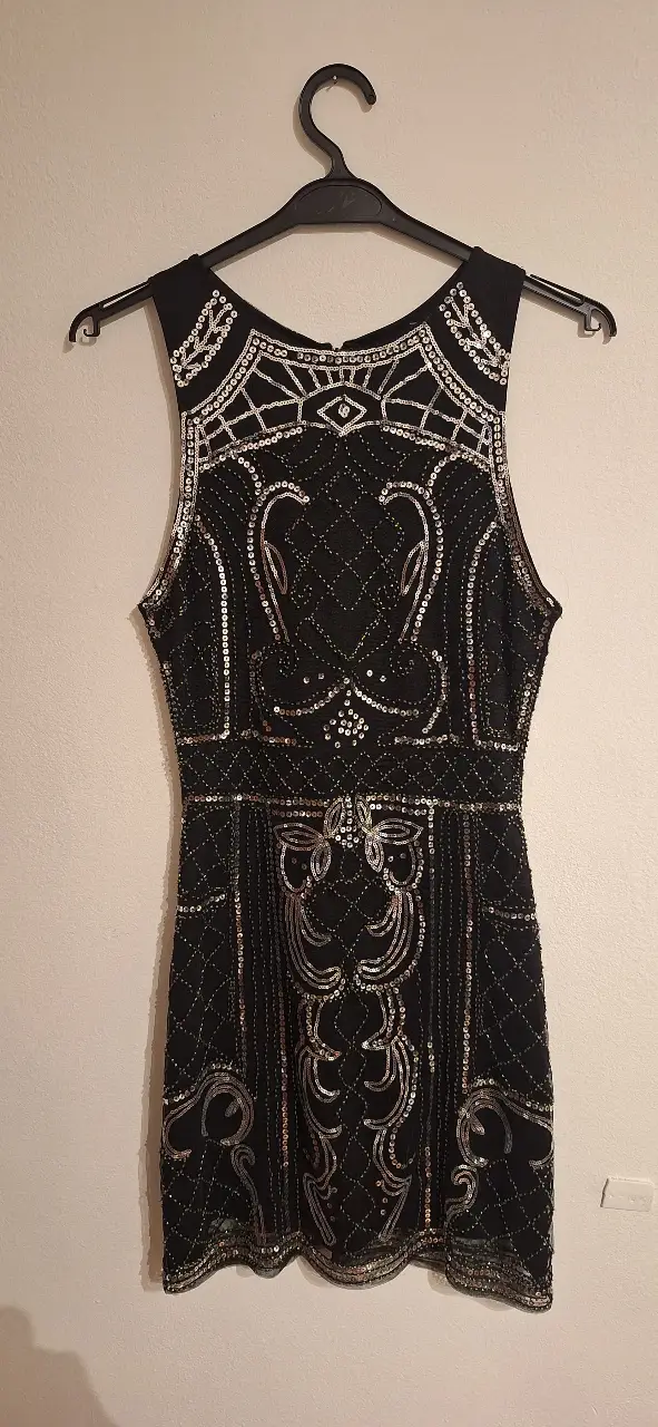 Vestido mini negro de fiesta con detalles plateados y lentejuelas. Ideal para eventos especiales y salidas nocturnas. Diseño elegante y sofisticado.