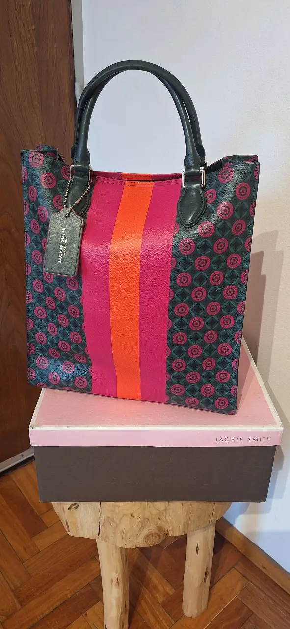Bolso tote de Jackie Smith, con diseño geométrico en tonos verde oscuro y rosa, con detalles en naranja y manijas negras. Incluye etiqueta de la marca. colección monograms.