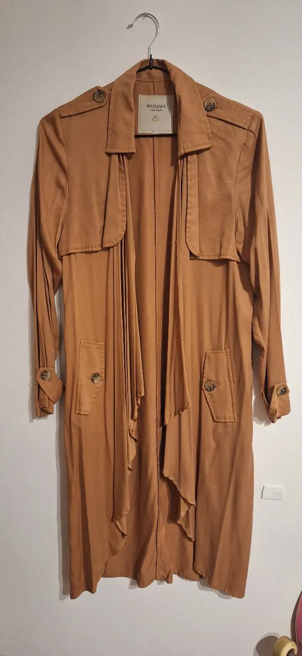 Trench coat de la marca Wanama, color marrón. Ideal para un look elegante y sofisticado. Confeccionado con materiales de alta calidad, este trench es perfecto para la temporada de otoño e invierno. Posee un diseño clásico con detalles modernos, como solapas amplias y bolsillos funcionales. Un abrigo versátil y atemporal que no puede faltar en tu guardarropa.