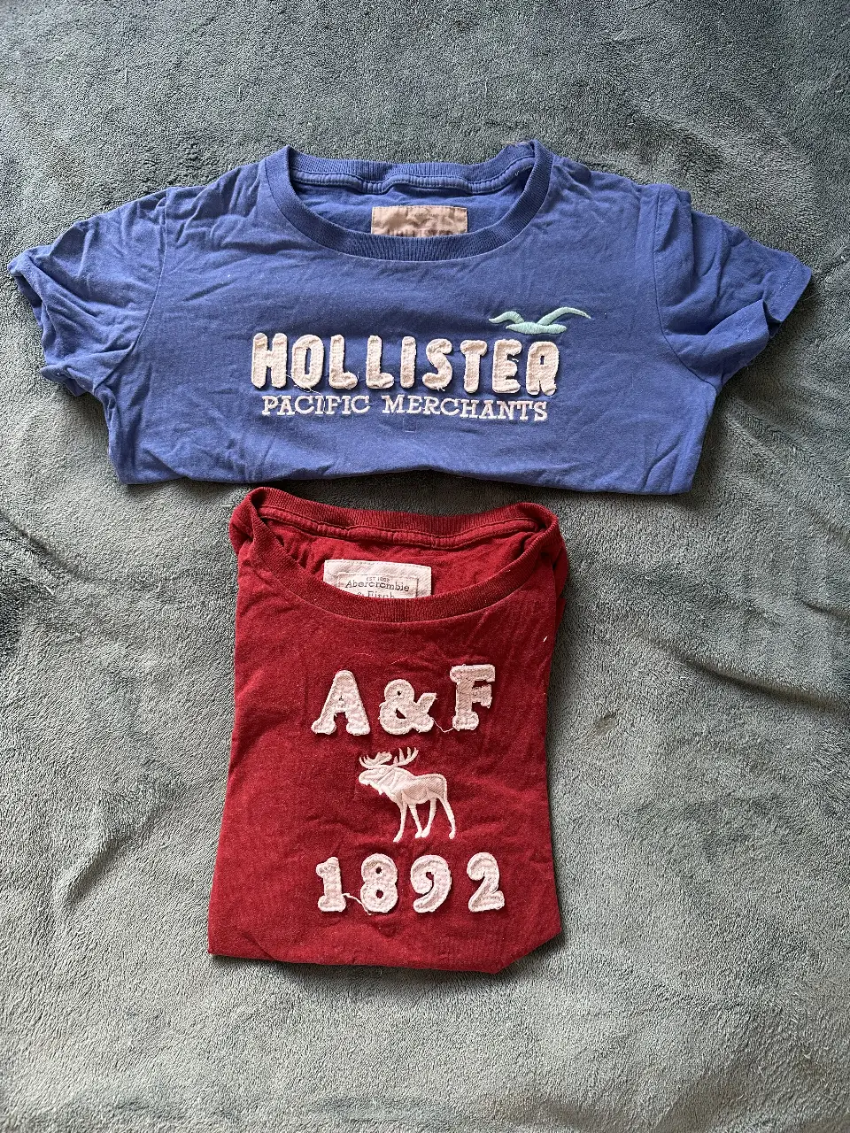 Remeras unisex Hollister azul con logo blanco en relieve y Bordo. Ideal para un look casual y cómodo.