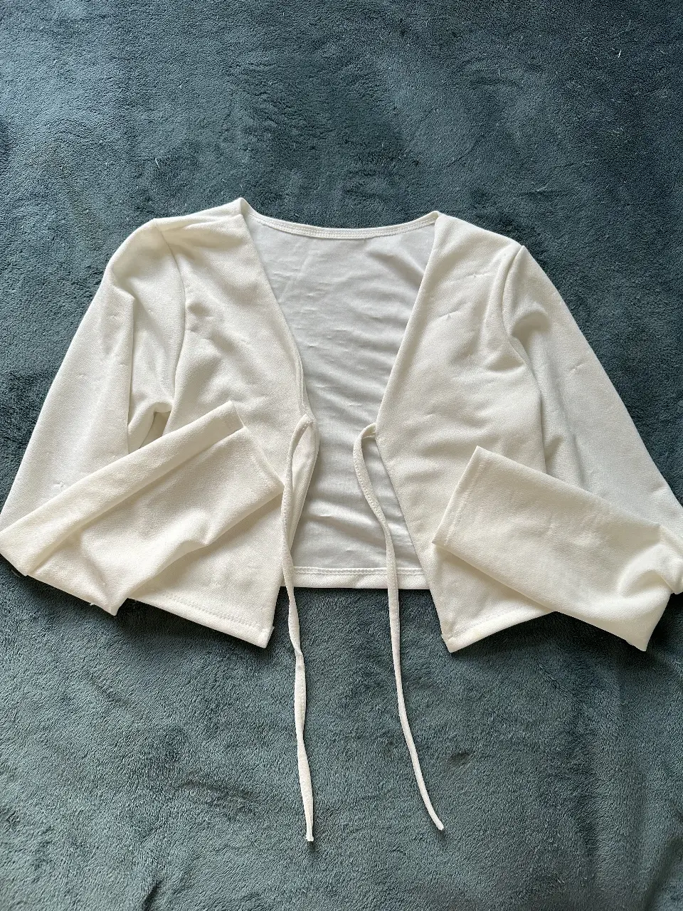 Cárdigan blanco de manga larga con lazos para atar. Ideal para un look elegante y versátil.