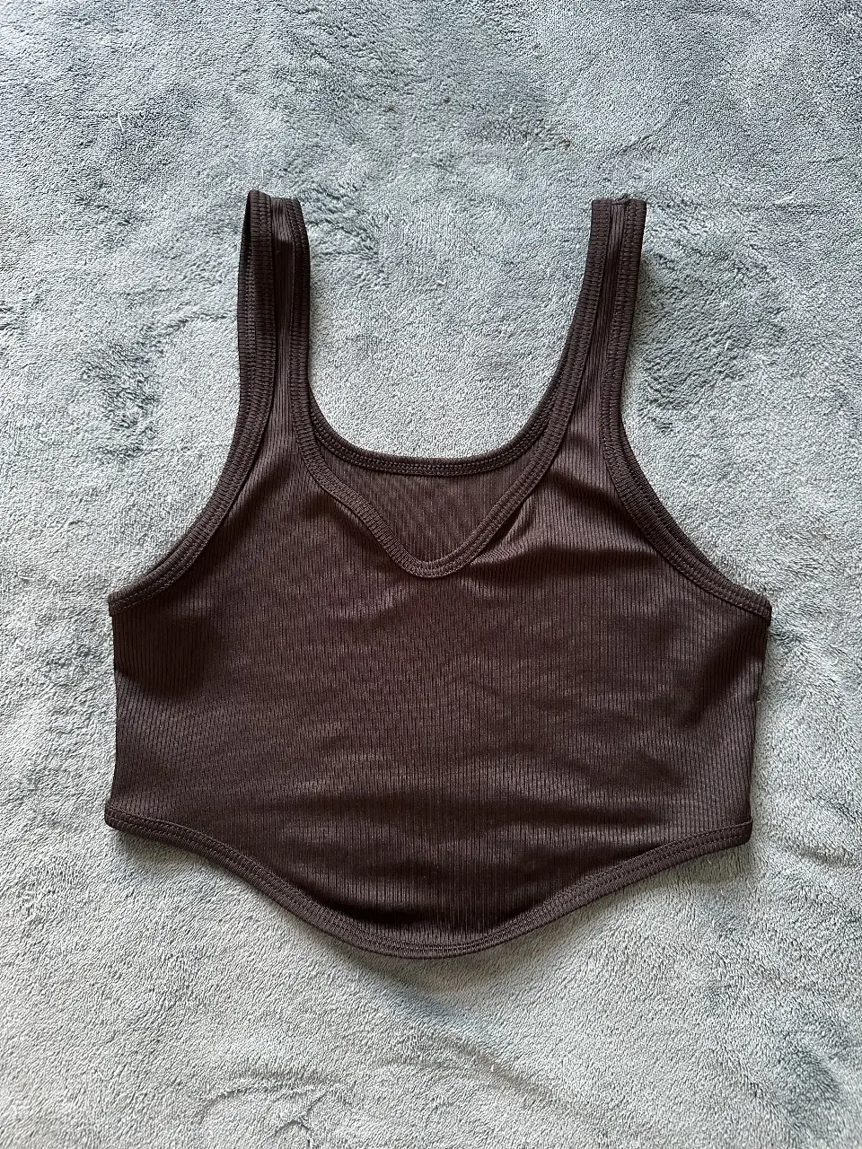 Top corto de tejido acanalado en color negro, ideal para un look casual y moderno. Diseño con escote en V y tirantes anchos.