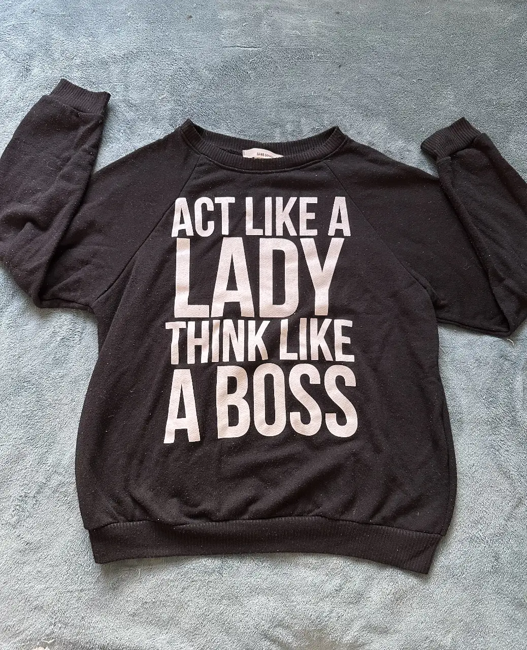 Buzo importado de cuello redondo negro con estampado "ACT LIKE A LADY THINK LIKE A BOSS" en blanco. Ideal para un look casual y con actitud.