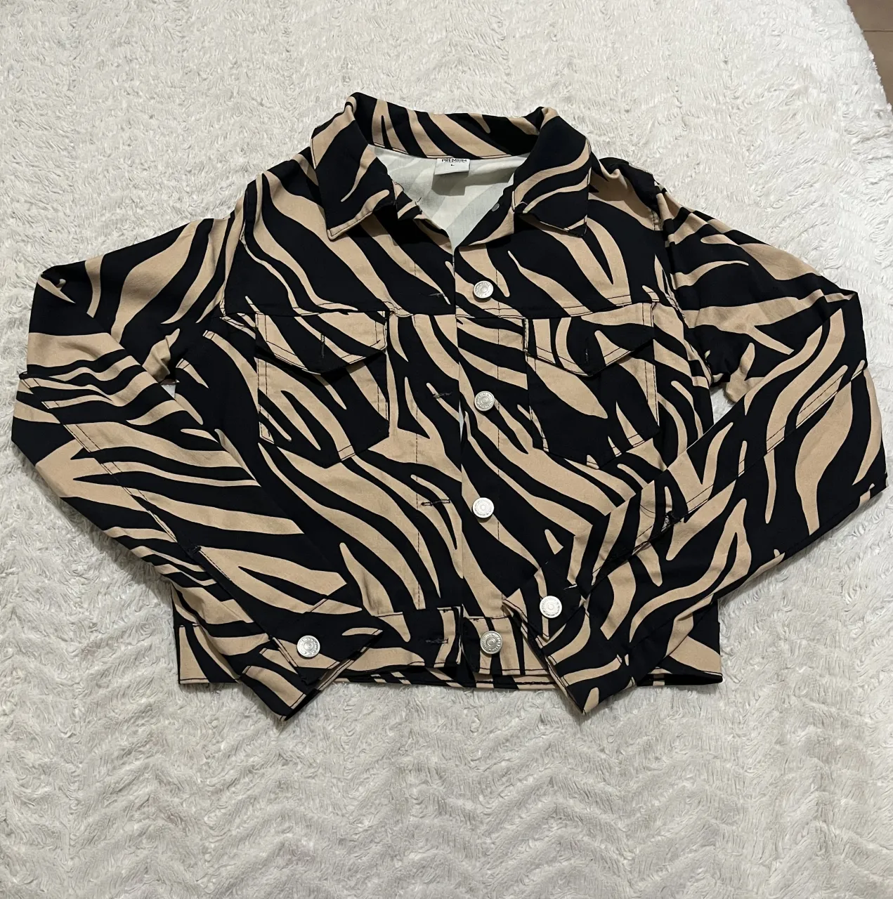 Campera de jean con estampa de cebra en blanco y negro. Tiene botones al frente y en los bolsillos.