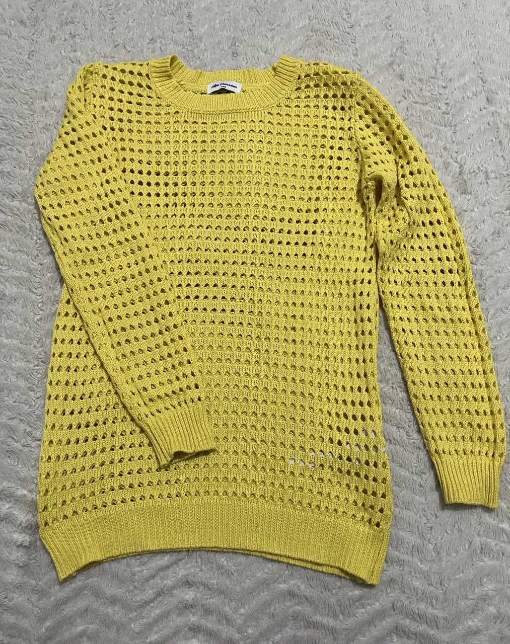 Sweater tejido amarillo con cuello redondo y mangas largas. Posee un diseño calado en toda la prenda.