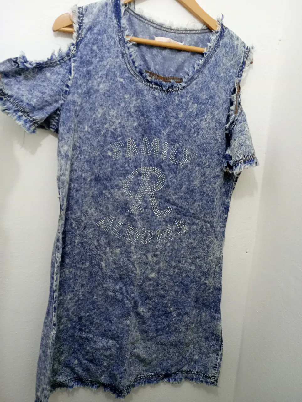 Vestido de jean con efecto desgastado y detalles de strass. Diseño moderno con hombros descubiertos y terminaciones deshilachadas. Ideal para un look canchero y urbano. abaca hasta un talle 4 cómodo y no es tan corto