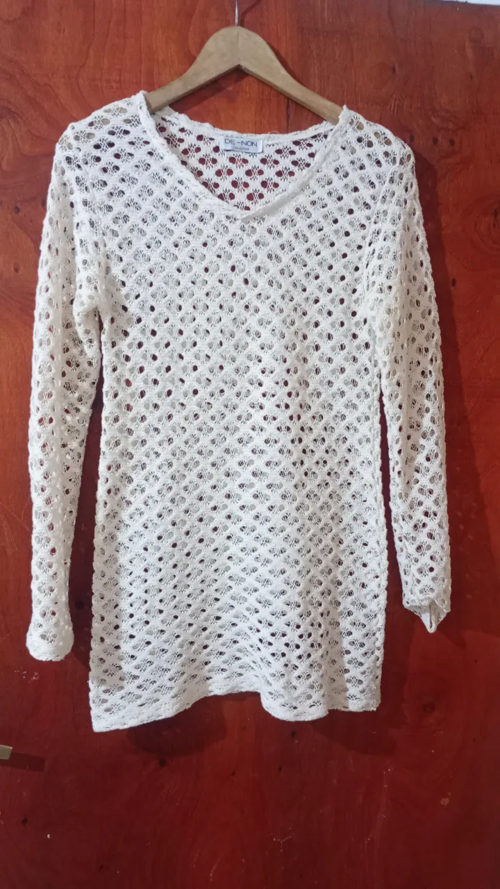 Remera blanca de hilo, manga larga, con un tejido calado muy delicado y diseño romántico. Ideal para usar sobre otra prenda o como salida de playa.