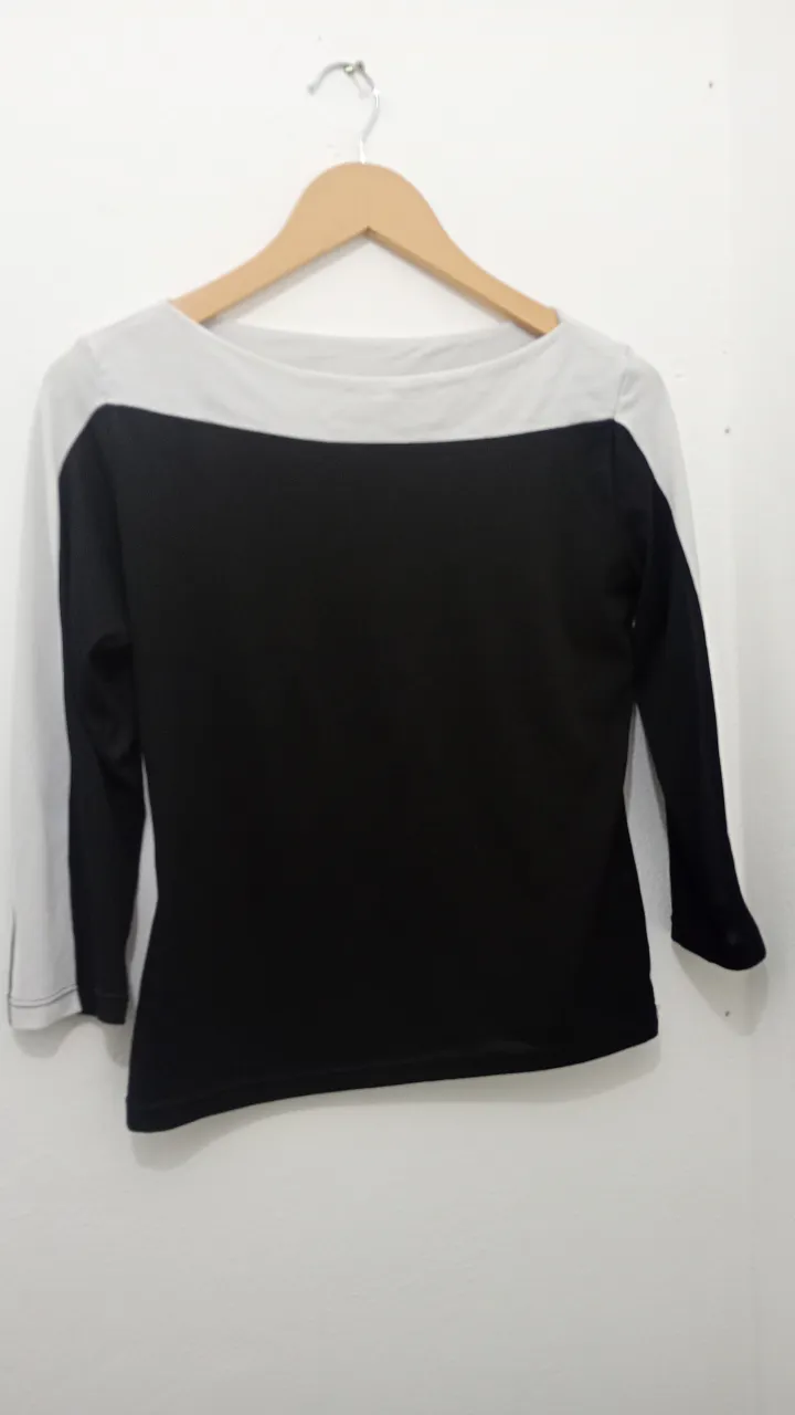 Remera manga 3/4 de Yessica, con diseño de dos colores, negro en el frente y blanco en las mangas y cuello. Ideal para un look casual y moderno.