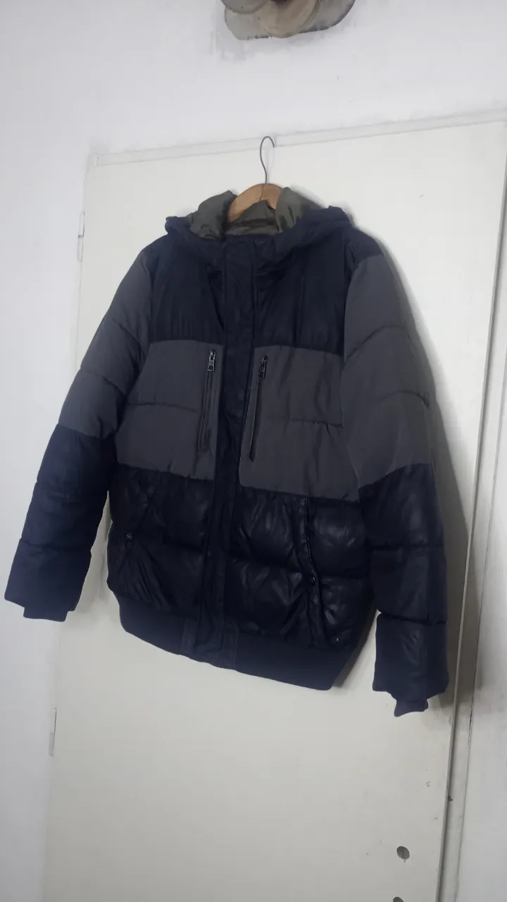 Campera acolchada con capucha, de varios paneles. Tiene cierre al frente y bolsillos con cierre en el pecho. Los puños y la cintura son de elástico.