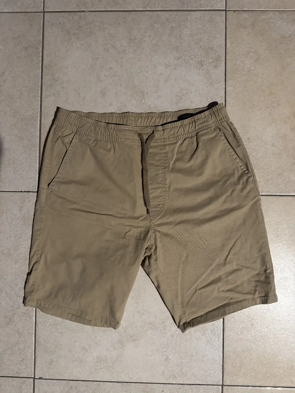 Short de hombre color khaki, con cintura elastizada y cordón. Bolsillos delanteros y traseros. Ideal para un look casual y cómodo.