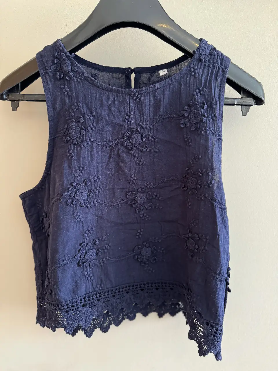 Top sin mangas de color azul marino con detalles florales en relieve y borde de encaje. Ideal para un look fresco y femenino.