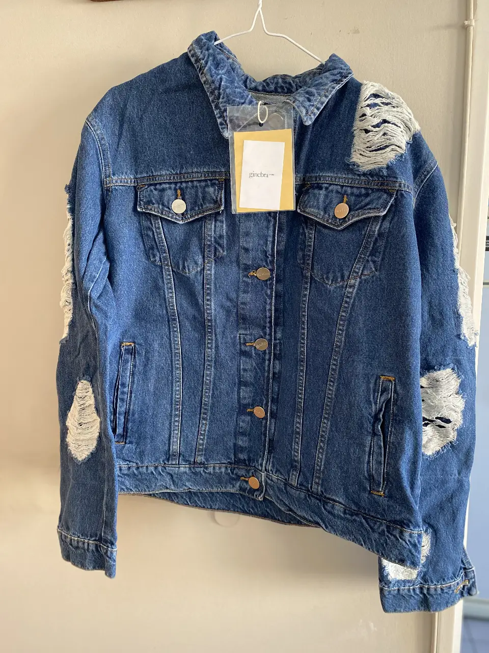 Campera oversize de jean azul con detalles rotos y la inscripción "GINEBRA LA MODE" en la espalda. Ideal para un look canchero y urbano. 