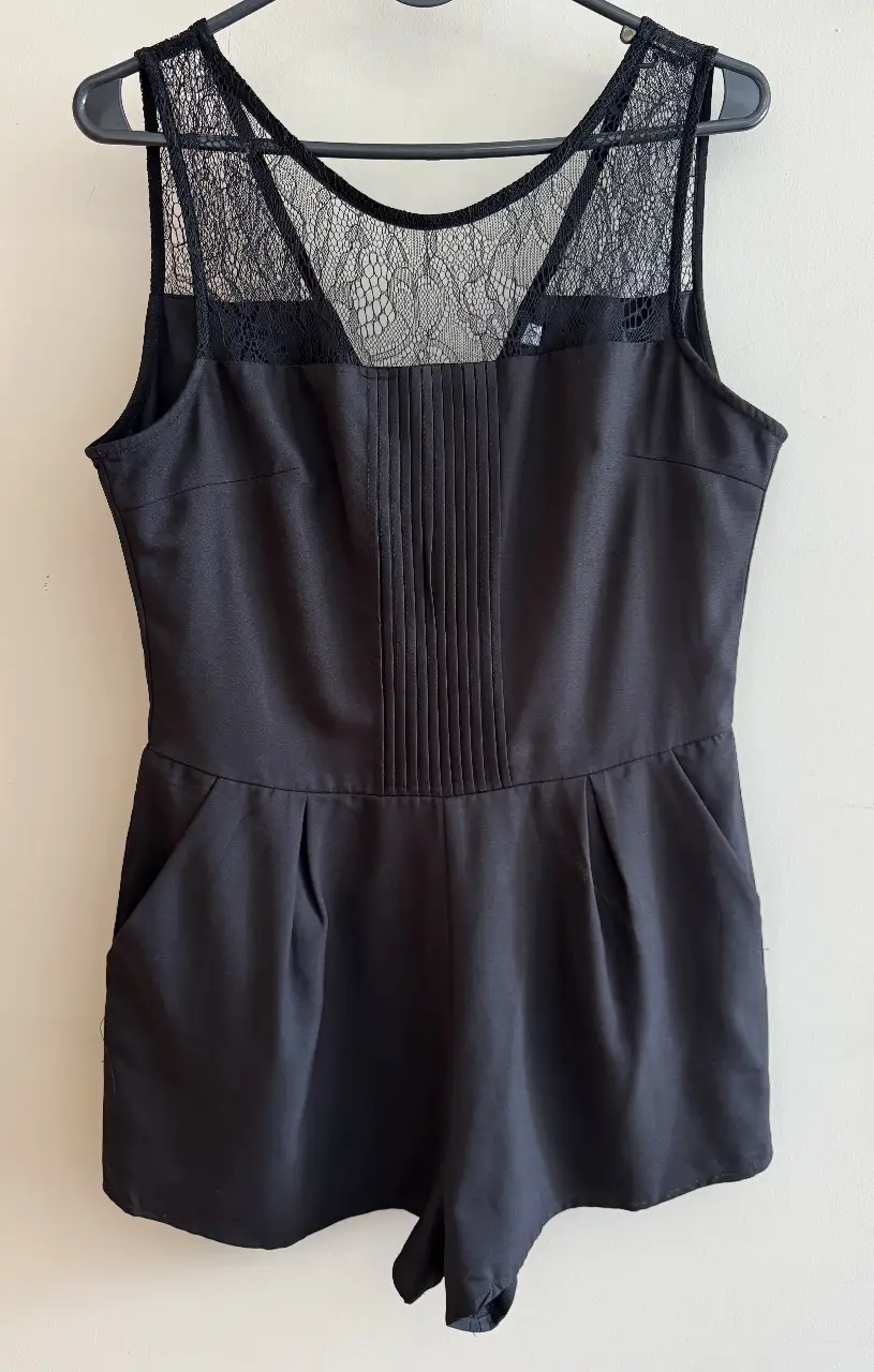 Mono corto negro con detalles de encaje en la parte superior y pliegues en la parte delantera. Ideal para una salida o fiesta.