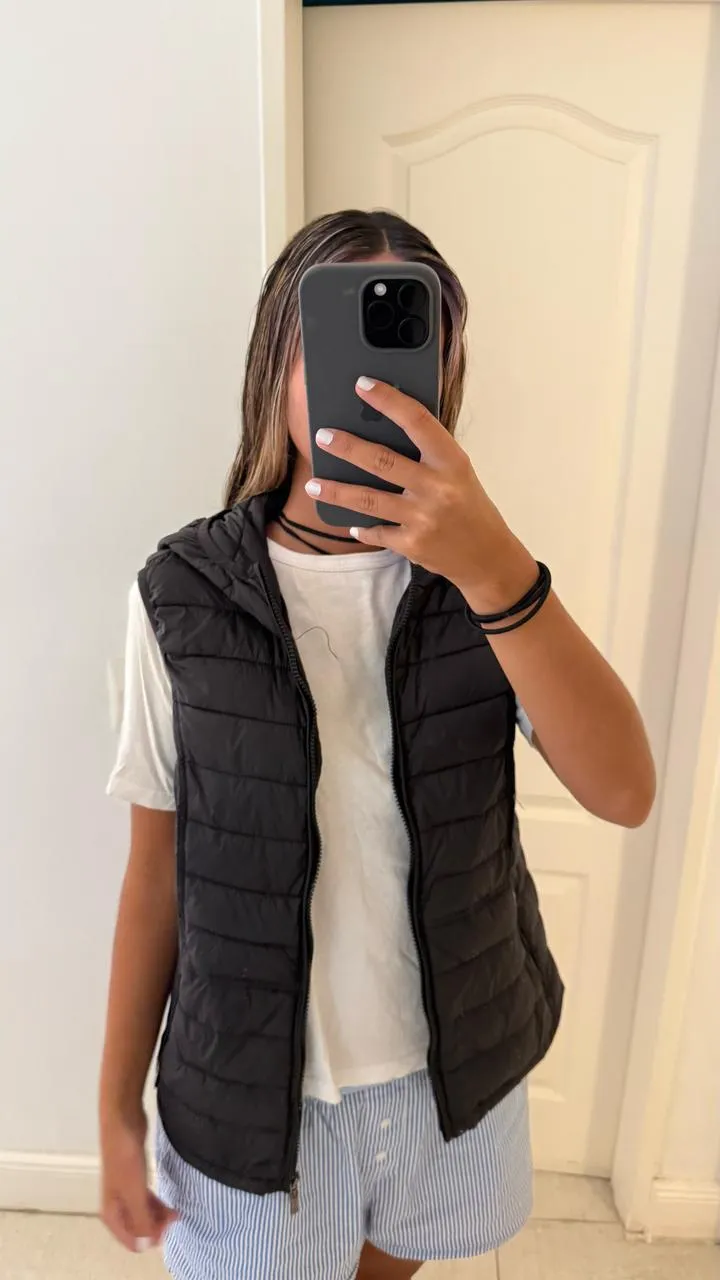Chaleco acolchado negro con capucha, tipo Uniqlo. Ideal para un look casual y abrigado.