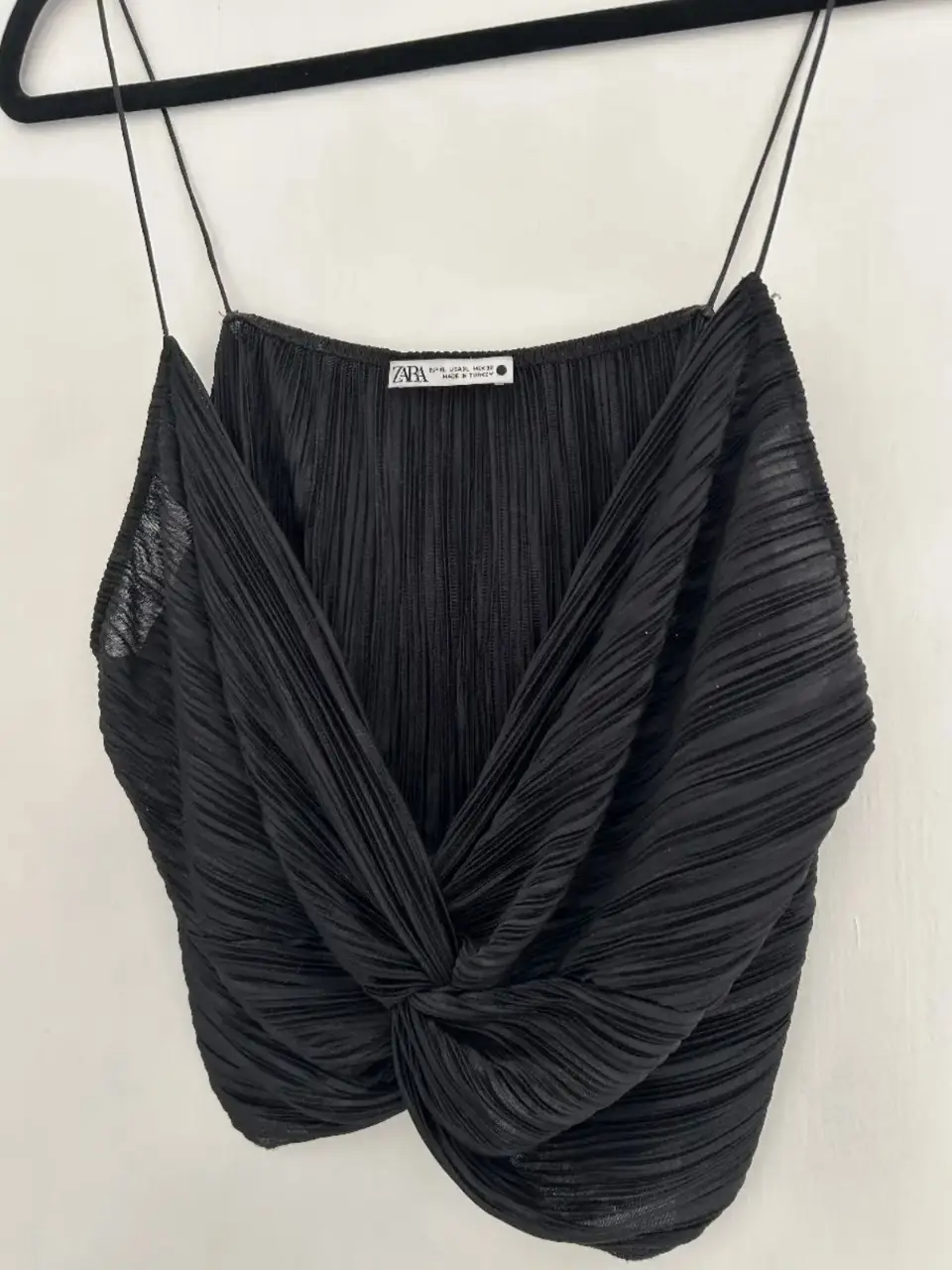Top negro de mujer, con diseño drapeado y anudado en la parte delantera. Ideal para un look elegante y moderno.